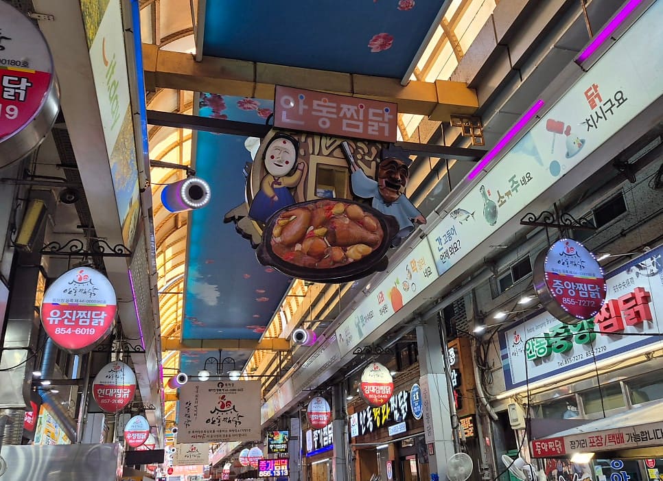 soulfulog가 찍은 골목 천장의 안동찜닭 간판과, 바깥 공영주차장 쪽 안내판입니다. 유진찜닭·현대찜닭·우정찜닭·중앙찜닭 간판이 한 장에 함께 걸려 있고,