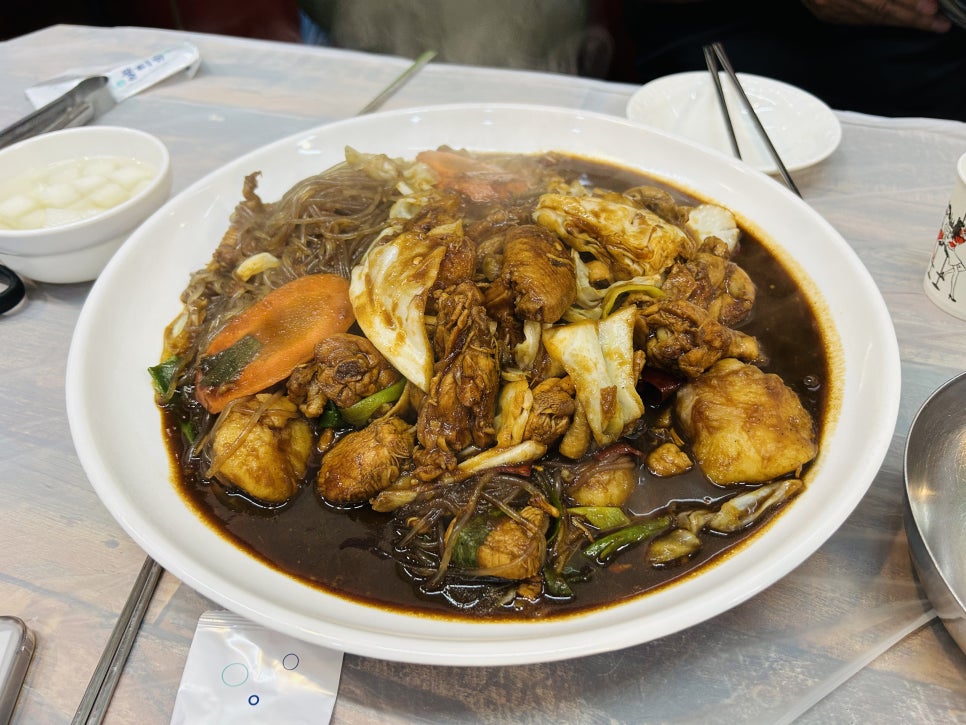 qkrdusqls님이 남긴 테이블과 찜닭 한 상입니다. 벽면에 원안동찜닭이라는 글자가 보이고, 메뉴는 단일 메뉴라 고민 없이 중자를 보통맛으로 주문했다고 적었습니다.