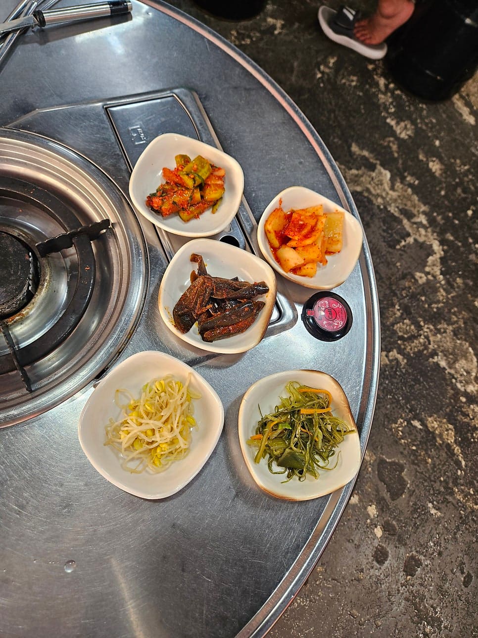 jjinjin2_는 깍두기·콩나물무침·오이무침 같은 밑반찬 다섯 접시를 가까이서, 그리고 대파와 두부가 올라간 김치찌개가 보글보글 끓는 모습을 클로즈업으로 남겼다.