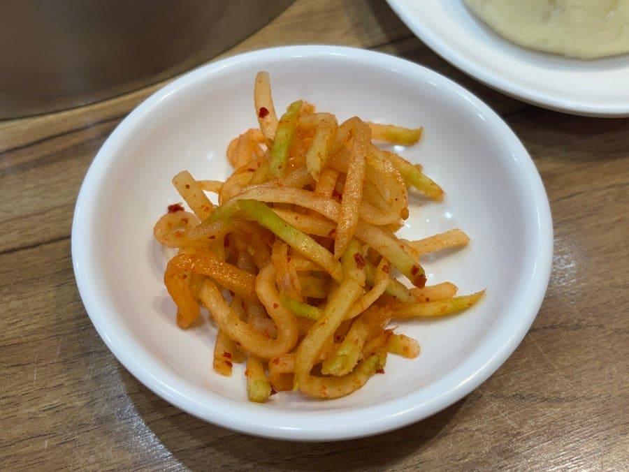 fnrakf97은 찜통에서 막 꺼낸 작은 만두와 왕만두, 그리고 셀프로 덜어온 무생채 한 접시를 찍었다. 소스 그릇은 각자 입맛대로 채워 넣게 비워져 있었다.