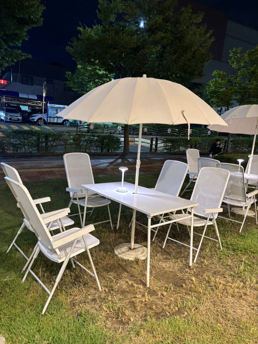 밤의 테라스 좌석입니다. 파라솔이 설치된 테이블과 편한 의자, 잔디밭이 어우러져 도시 속에서 자연을 느낄 수 있게 해줍니다.