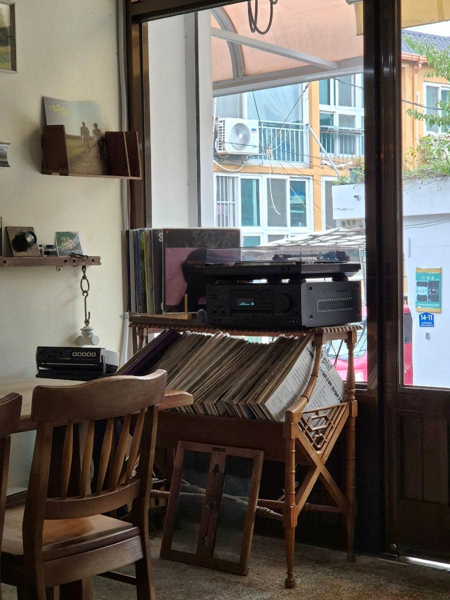 dailyonsdot이 찍은 마농커피의 창가 자리입니다. 오래된 벽시계와 액자가 걸린 벽, 턴테이블과 빼곡히 꽂힌 LP판이 사장님이 고른 음악의 출처를 보여줍니다.