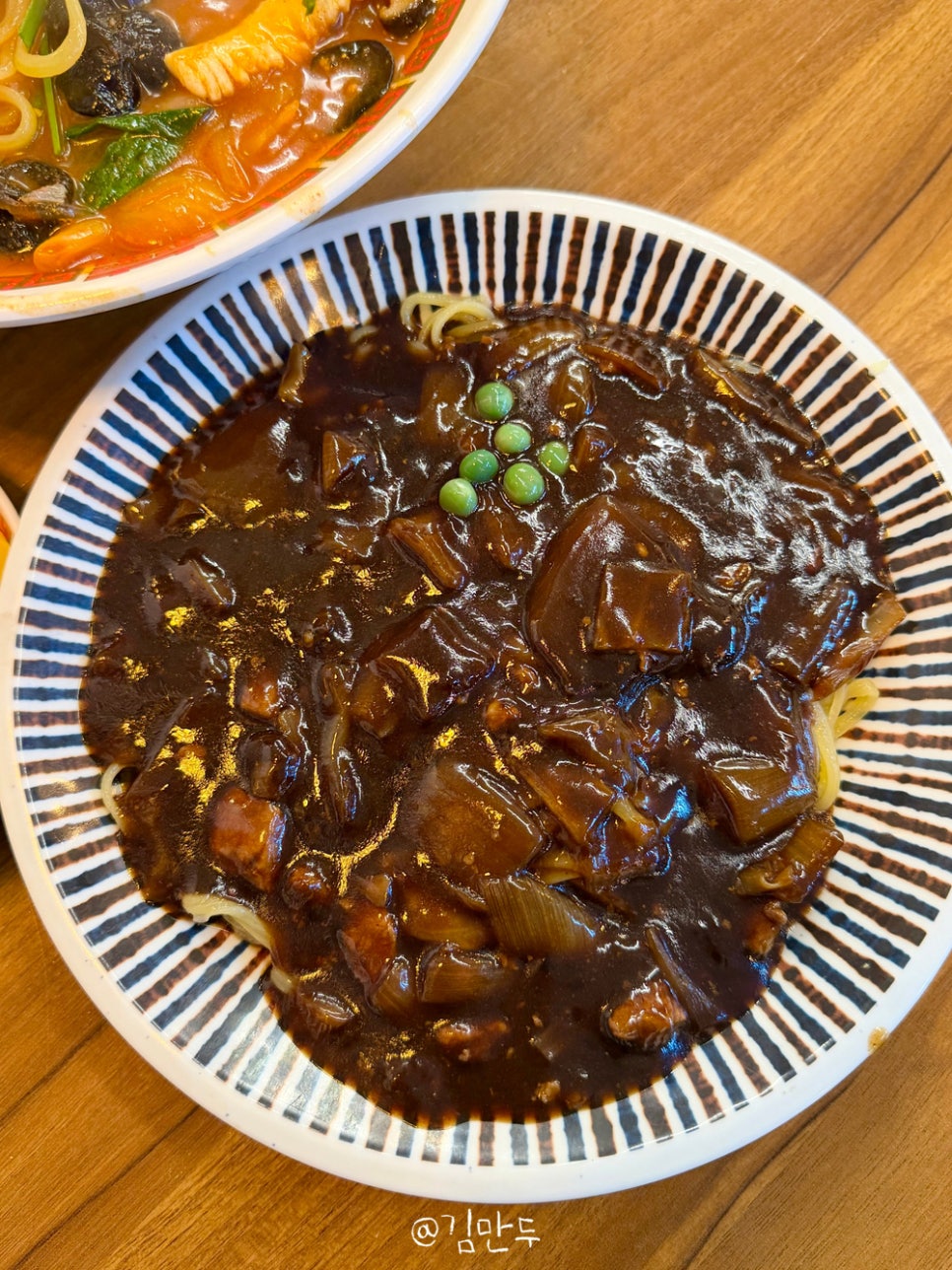 mandu_u가 남긴 반찬 그릇과 면 사진입니다. 매운 김치와 노란 단무지가 담긴 접시, 젓가락으로 들어 올린 짜장면 가락에서 셀프바 반찬과 분주한 점심 풍경이 함께 묻어납니다.