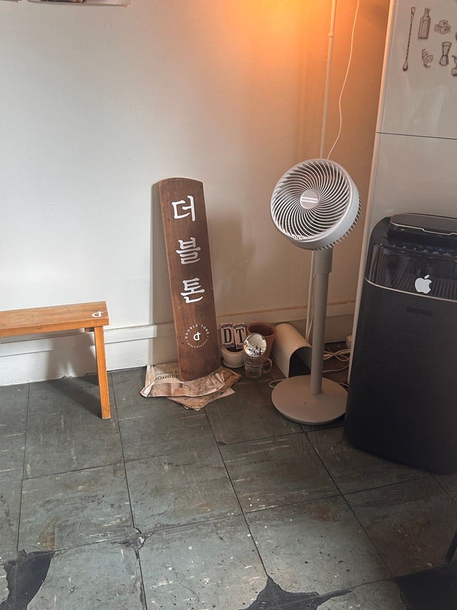 같은 사람이 남긴 '더블톤' 나무 간판 사진입니다. 선풍기와 벤치 옆, 낡은 신문지 위에 세워둔 간판 글자가 정겹습니다.