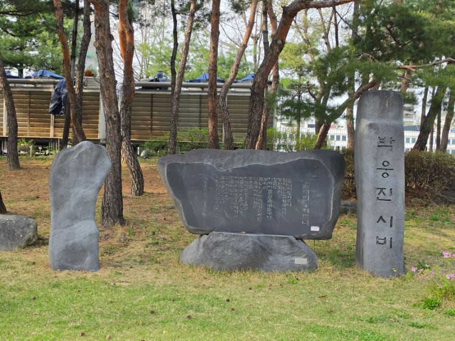 같은 사람이 남긴 박웅진 시인의 시비 사진입니다. 소나무 사이 세워진 검은 돌에 시구가 새겨져 있습니다. 운동기구로 몸을 움직이러 온 사람들 곁에,