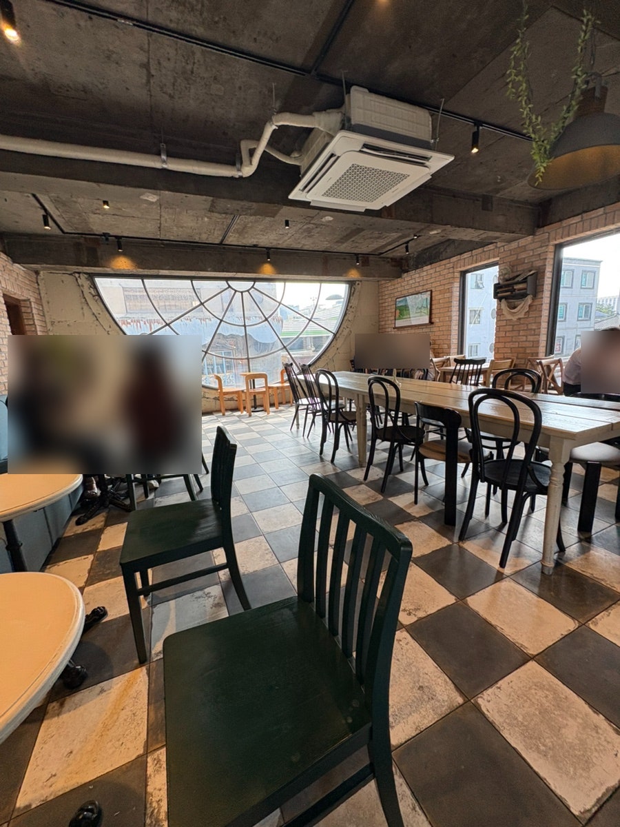 긴 테이블이 놓인 위층입니다. 거미줄 모양의 커다란 둥근 창과 체크무늬 바닥, 벽돌 벽이 어우러져 있었습니다.