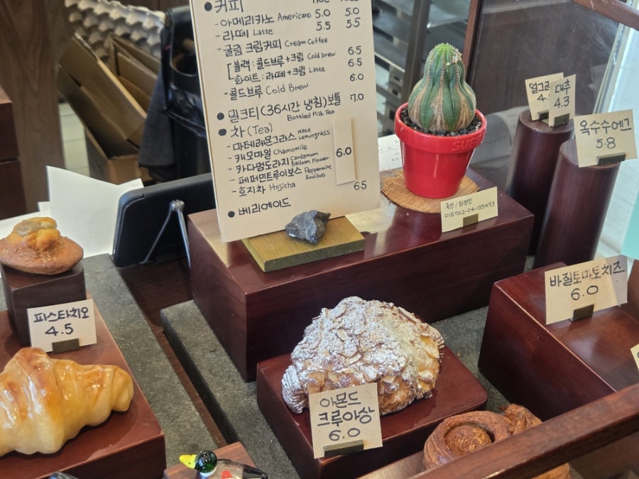ri_fam이 찍은 메뉴판과 계산대 옆 작은 선인장입니다. 커피와 밀크티, 차 종류까지 메뉴가 다양했는데, 아몬드 크루아상 앞에서도 한참을 고민했다고 적었습니다.