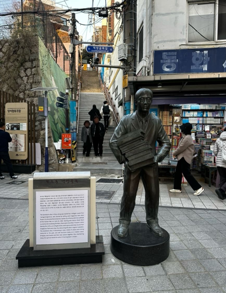 가족과 함께 찾은 방문자는 골목 입구의 책 든 동상과 계단, 그리고 헌책 매대가 늘어선 골목 안쪽 풍경을 함께 남겼습니다.