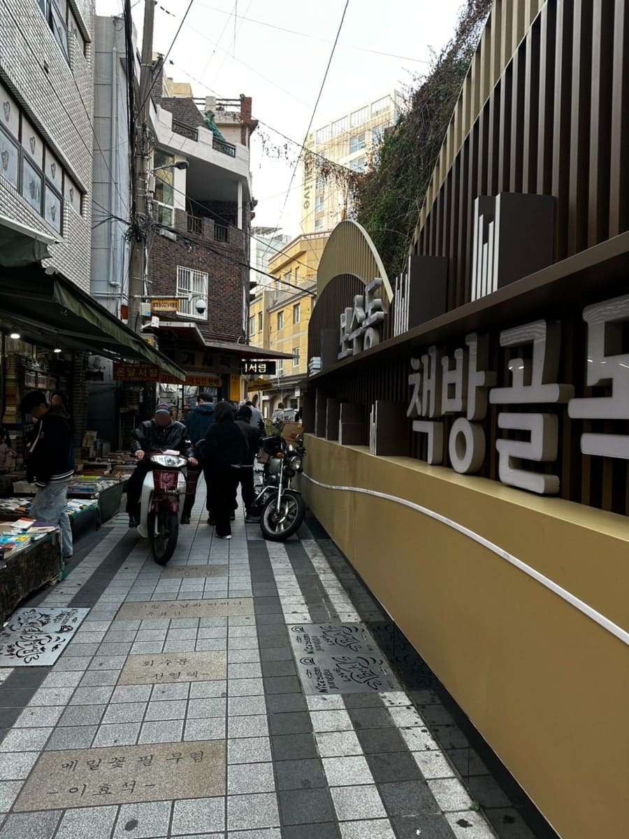 가족과 함께 찾은 방문자는 골목 입구의 책 든 동상과 계단, 그리고 헌책 매대가 늘어선 골목 안쪽 풍경을 함께 남겼습니다.