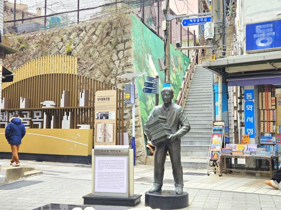 책 더미를 품에 안은 손정린씨의 동상이 골목 초입, 책방골목길 표지판 아래에 서 있다. 계단 옆 동화서점 매대에는 아이들 책이 가득 쌓여 있다.