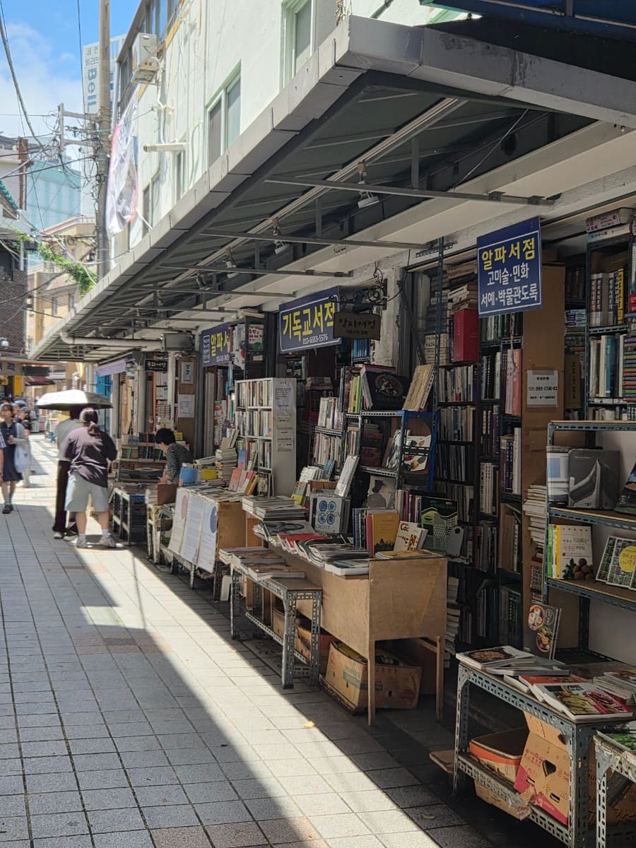 보수서점 모퉁이 간판과, 좌판 위에 책을 쌓아 올린 골목 안쪽 풍경이다. 지금도 문을 여는 서점들이 볕 좋은 날 거리로 책을 내놓는다.