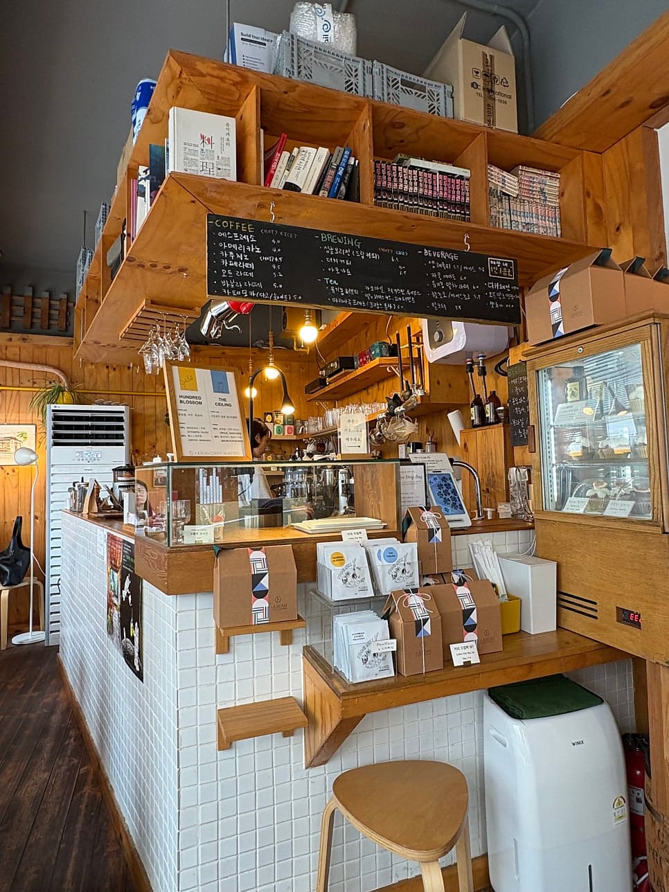 한 블로거는 창가 자리에 앉아 골목 밖 풍경까지 들어오는 나무 톤 좌석을, 다른 블로거는 책과 원두 봉투가 함께 놓인 카운터를 남겼습니다.