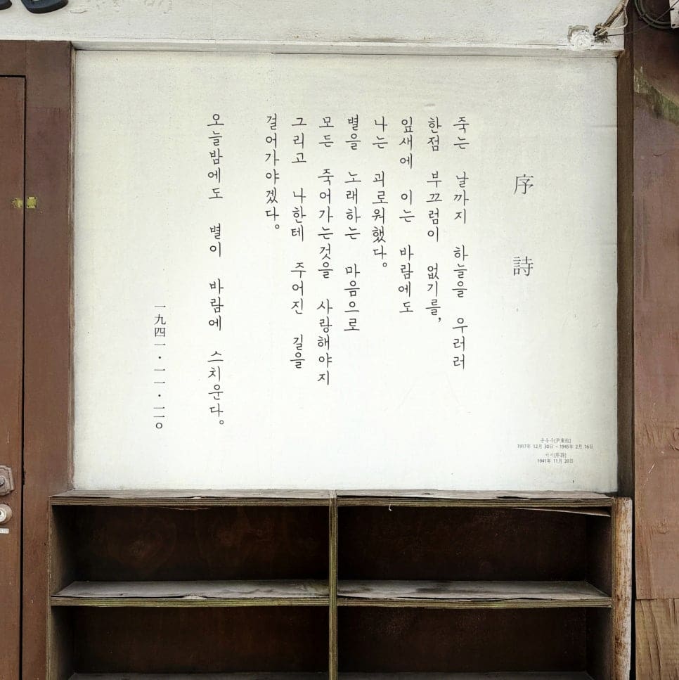 풀이 돋은 돌계단과, 텅 빈 나무 선반 위에 걸린 오래된 시 한 편이다. 계단을 오르내리는 발소리와 낡은 종이의 정적이 함께 있다.