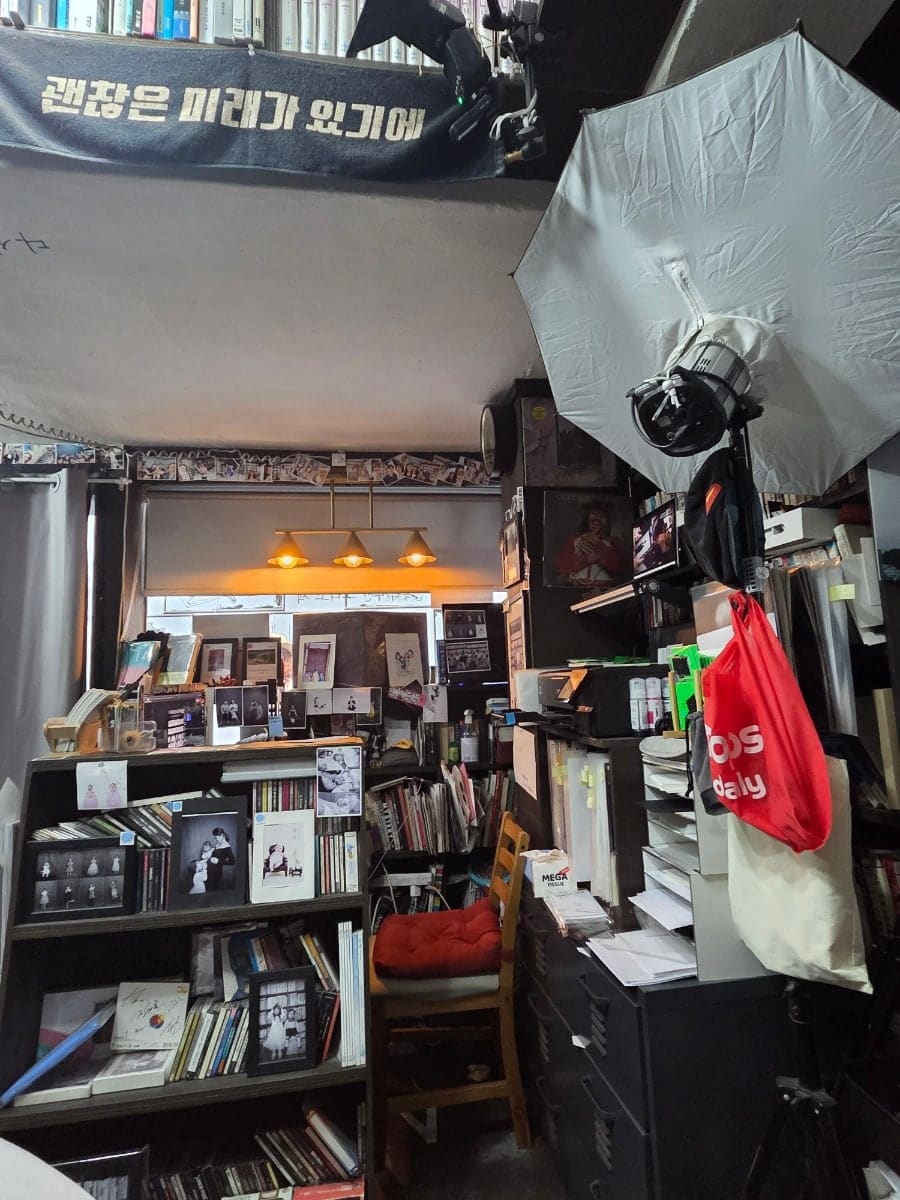 촬영 배경 커튼과 조명 장비, 그리고 그동안 다녀간 손님들의 즉석사진이 빼곡히 붙은 거울 옆 벽면입니다.