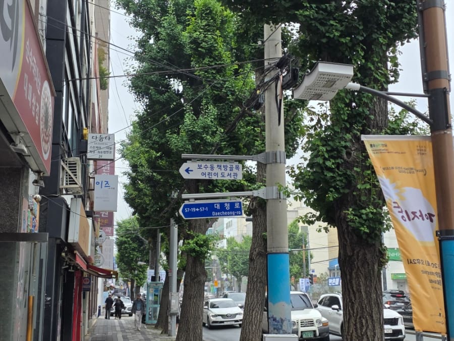 책방골목 어린이 도서관 방향을 가리키는 표지판과, 대영서점 간판 아래로 사람들이 오가는 골목 초입이다. 헌책방은 지금도 이 자리에서 문을 연다.