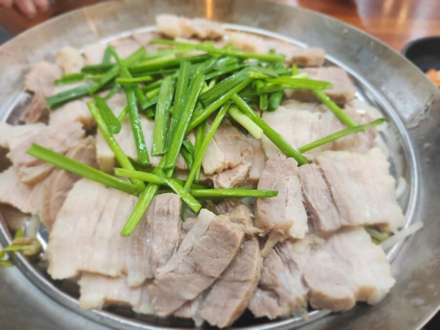 1216wngusdl 님이 남긴 삼겹수육 한 접시와, 깻잎에 밥과 고기를 올려 쌈을 싼 장면입니다. 잡내 없이 깔끔하고 씹을수록 육즙이 느껴진다고 적었습니다.