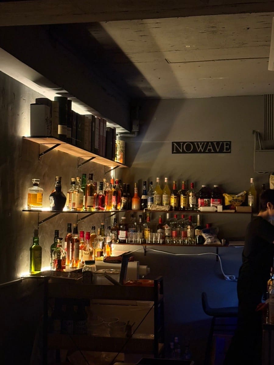 ch990130이 담은 바 안쪽입니다. 선반 가득 늘어선 위스키·리큐르 병과 'NOWAVE' 글자 조명, 그리고 바 테이블 위에서 빛나던 칵테일 한 잔까지.