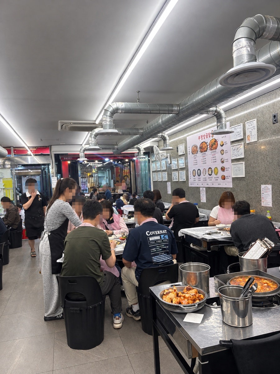 밤이 되어 네온 간판에 불이 들어온 돼지국밥집 외관과, 손님으로 가득 찬 양곱창집 실내입니다. 낮 동안 조용하던 자리가 저녁이면 테이블 손님과 웨이팅 줄로 채워집니다.