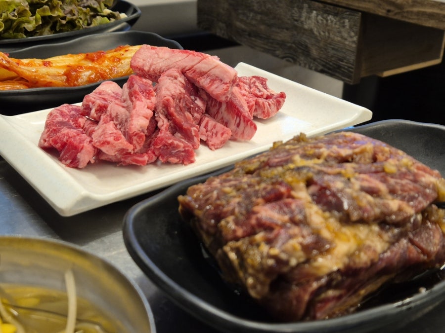 환풍관이 줄지어 늘어선 좁은 통로를 따라 드럼통 테이블이 이어집니다. 소갈비살이 상 위에 놓인 모습을 두고 이 블로거는 착한 가격의 푸짐한 양이 시장 식당의 매력이라고 적었습니다.