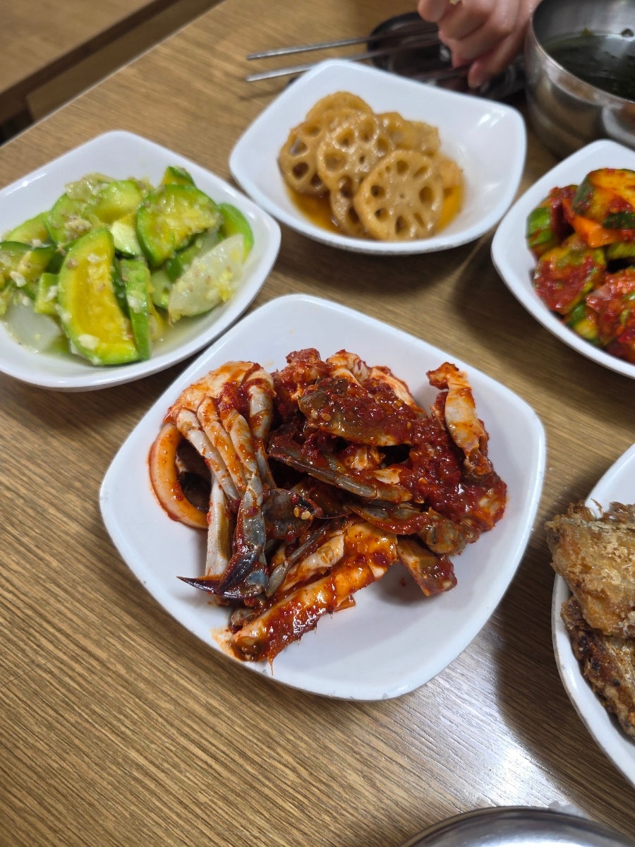 검게 그을린 무쇠 불판 위에서 생선 토막이 구워지고 있고, 매콤하게 무친 꽃게무침과 오이무침, 연근조림이 상 위에 함께 놓였습니다.