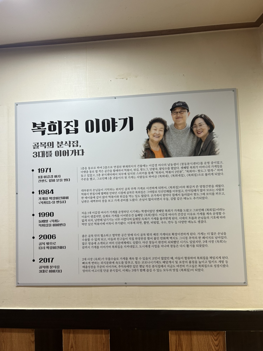 hankong__이 담은 매장 안 연혁 안내판과 떡볶이·김밥 상입니다. 1971년 간판 없이 시작해 3대를 거쳐 온 가게의 내력이 사진 속 안내판에 그대로 정리돼 있습니다.