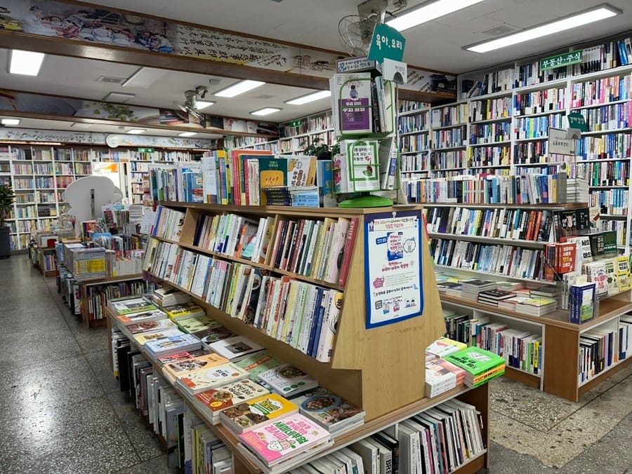 hyerok95가 담은 서점 입구와 책장입니다. 색이 바랜 스케치북과 분야별로 정리된 책장이, 70년 넘은 서점의 지금을 보여줍니다.