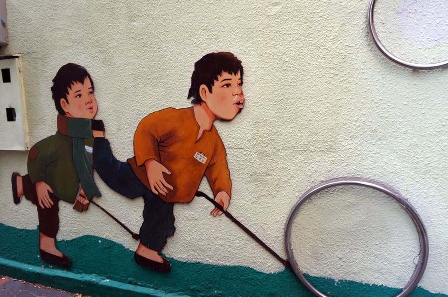 dkzdmom이 골목을 돌며 찍은 벽화 두 점입니다. 굴렁쇠를 굴리는 아이들과 하늘을 나는 천사들, 서로 다른 벽면이지만 같은 걸음으로 이어 담았습니다.