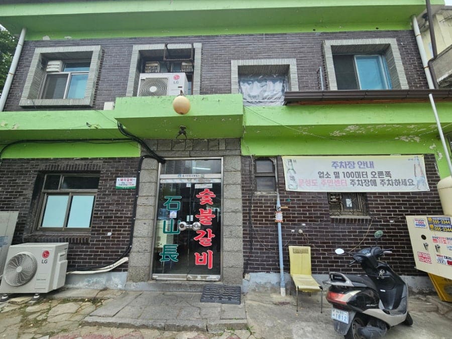 eiru2004가 문화로의 노포 석산장을 찾아 찍은 사진입니다. 40년 가까이 자리를 지킨 벽돌 건물 외관과, 여름휴가 안내문이 붙은 숯불갈비 간판 글씨를 가까이서 담았습니다.