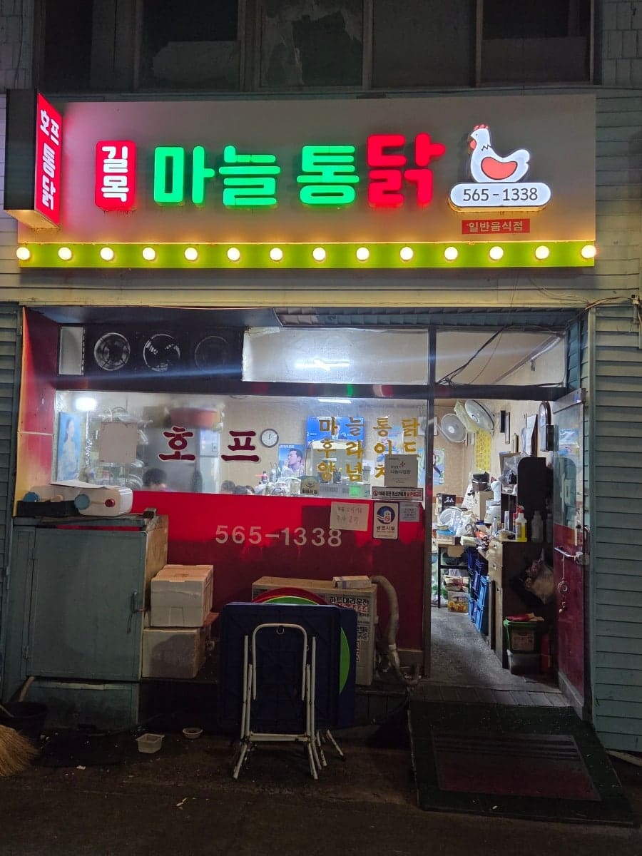 minjung_s가 노포 치킨집 길목마늘통닭을 찾아 찍은 사진입니다. 세월이 느껴지는 간판에 불이 켜진 밤의 가게 앞과, 벽에 붙은 노란 메뉴판을 함께 담았습니다.