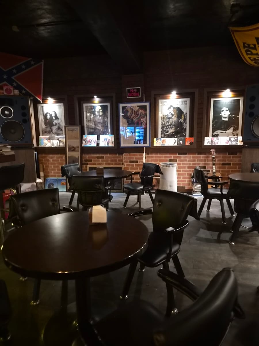 mjustm이 지하 LP바 롤링스톤즈에서 찍은 사진입니다. 벽 한 면을 채운 음반들과 뮤지션들의 흑백 사진, 둥근 백열등 조명이 늘어선 바 자리를 담았습니다.