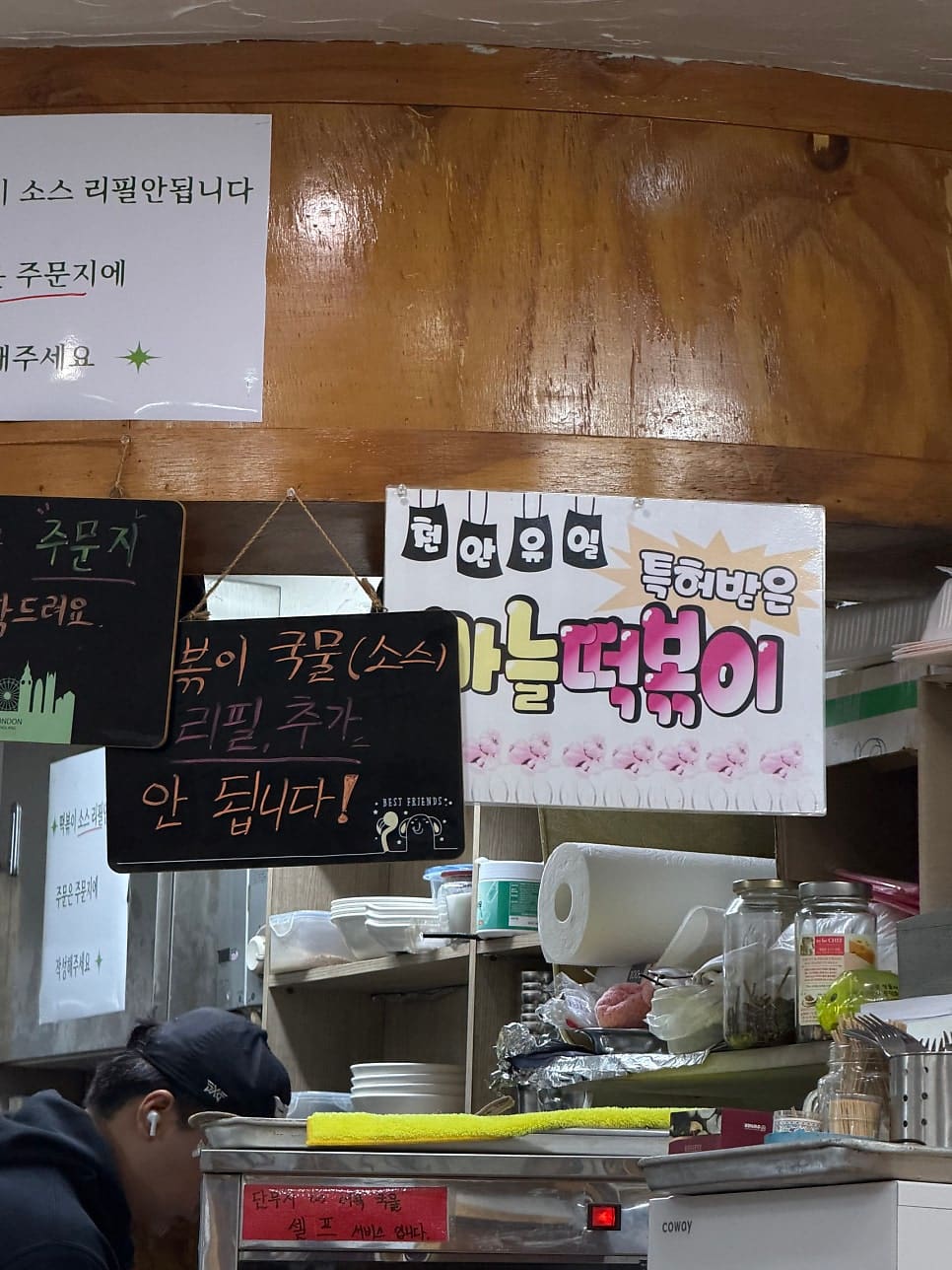 매장 안쪽 벽에 걸린 손글씨 안내판입니다. 소스 리필이 안 된다는 당부와 함께 특허받은 마늘떡볶이라는 문구가 붙어 있습니다.
