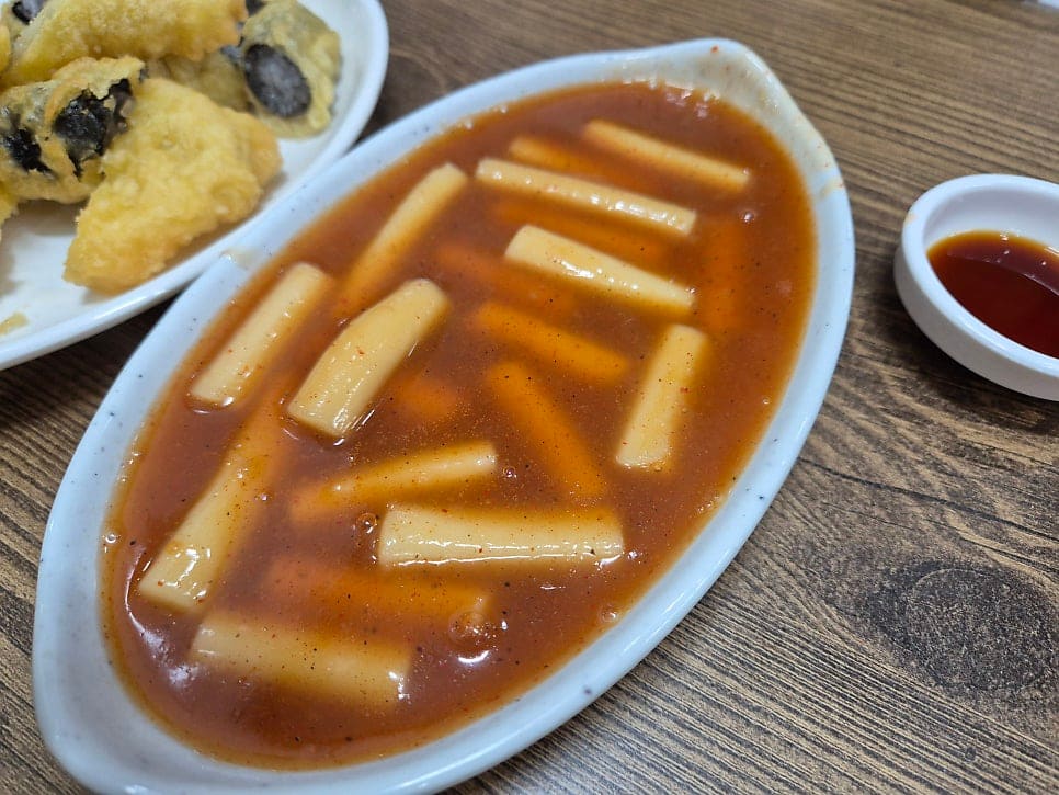 같은 상의 떡볶이를 가까이서 찍은 사진입니다. 국물이 맑고 묽어 보여서 의아할 수 있지만 한 입 먹으면 반전이 온다고, 후추와 마늘 특유의 알싸한 맛이 중독적이라고 적었습니다.