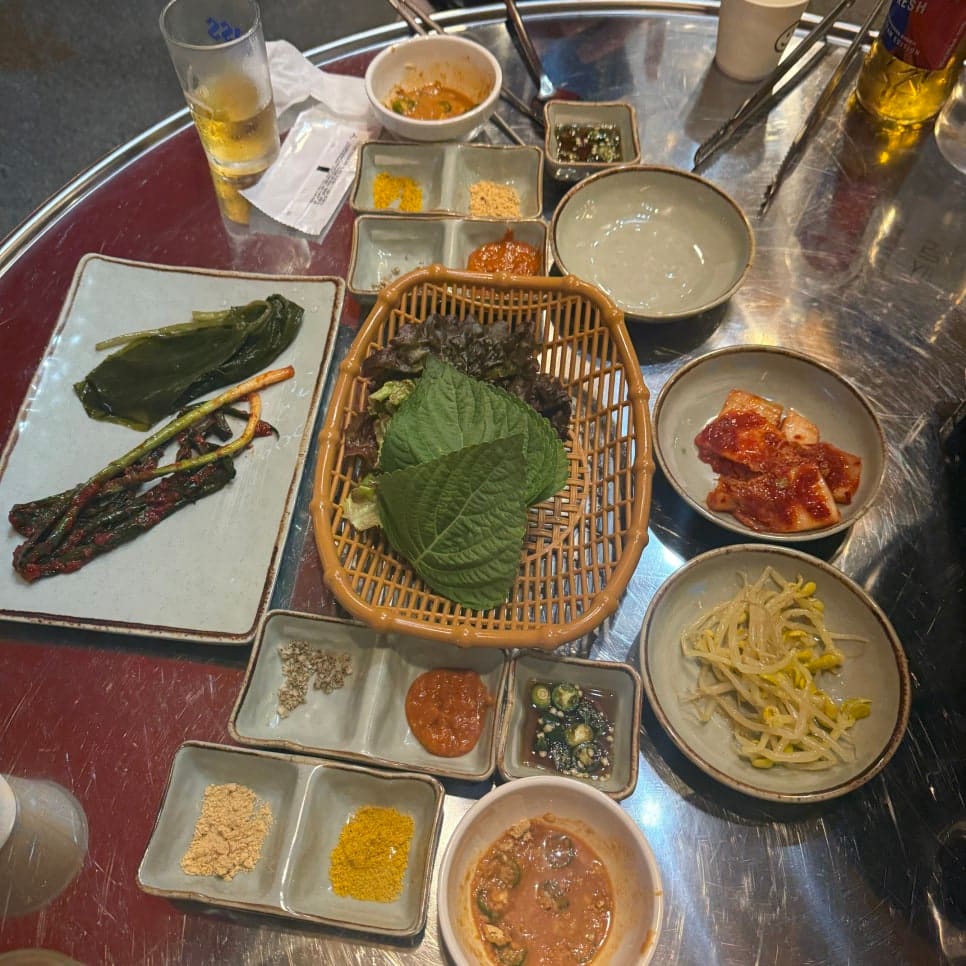 테이블 위에 차려진 기본찬입니다. 상추와 깻잎, 콩나물, 오이지, 겉절이까지 작은 그릇들이 빼곡합니다.