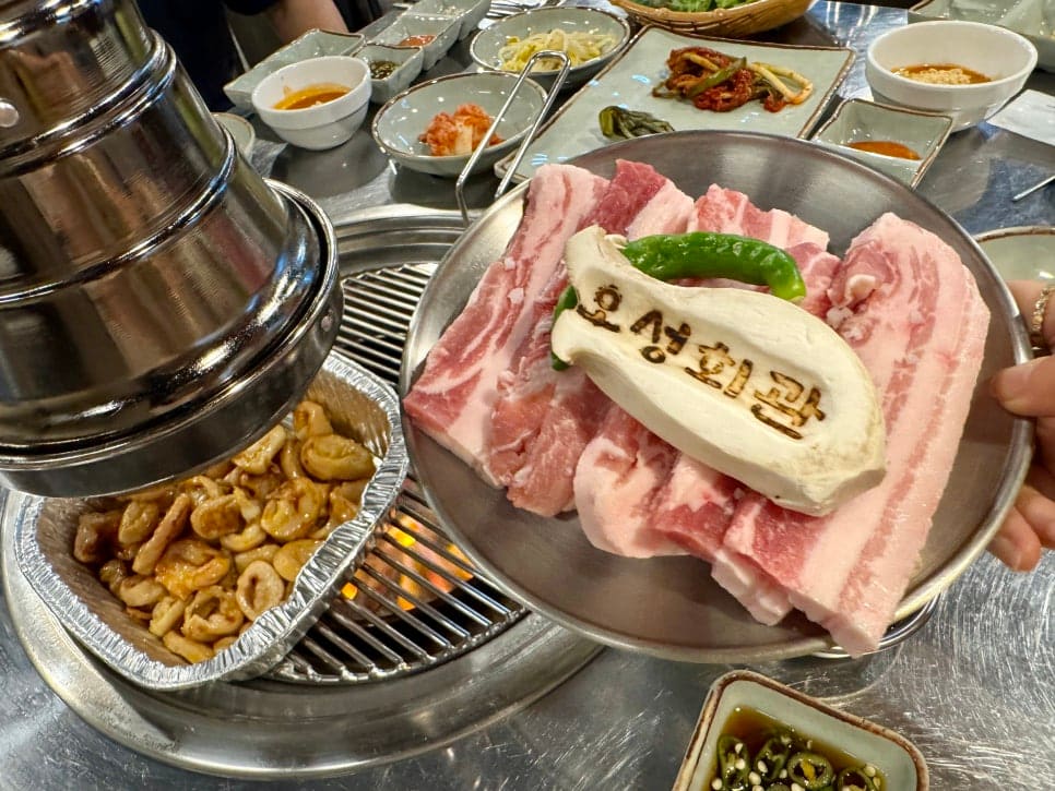 k5727710이 주문한 막창삼겹세트입니다. 나무 명찰에 오성회관이라는 글씨가 고기 위에 올라가 있습니다. 포차골목 특유의 감성과 맛있는 고기,