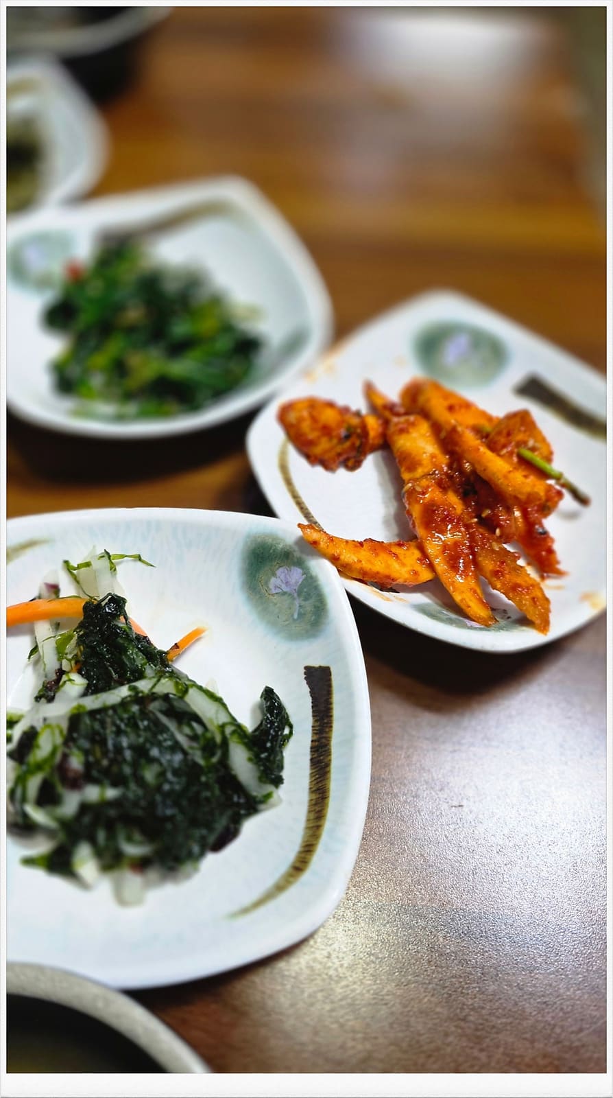 시금치 나물과 매콤한 어묵조림입니다. 꽃무늬가 그려진 접시 위에 소담하게 담겨 있습니다. 가자미구이, 야채전, 미역무침까지 상이 꽉 찰 정도로 반찬이 나온다고 적었습니다.