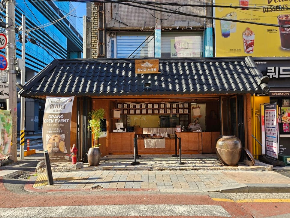 성안길 소금빵 가게 원미당 주변을 찍은 woniovehotwo의 사진입니다. 옆 건물 옥상에는 청주호떡·부산어묵을 함께 파는 간판이 걸려 있고,