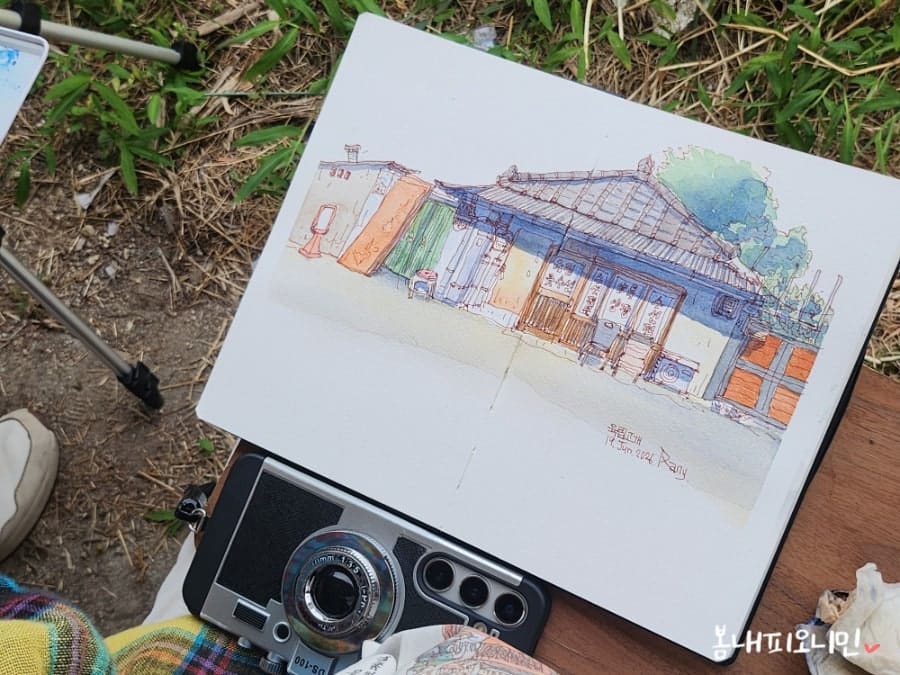같은 모임에서 minigmimemo가 남긴 사진입니다. 차양 그늘에 자리 잡고 앉아 그림을 그리는 일행의 모습과, 수채 물감으로 완성한 수선집 그림을 함께 담았습니다.