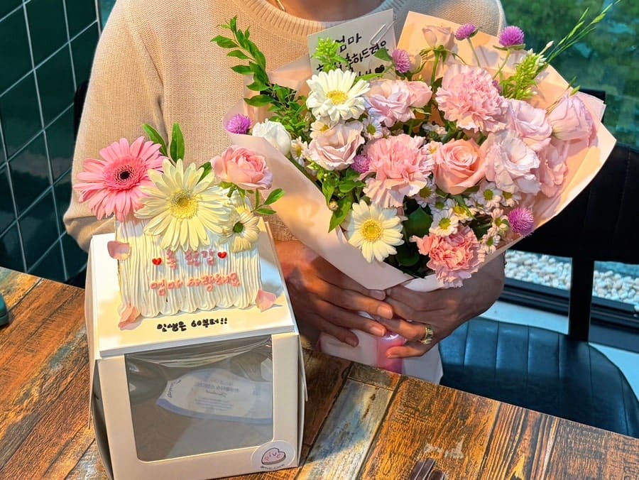 같은 날 kcho990929이 찍은 케이크 상자와 꽃다발입니다. 환갑 기념으로 함께 준비한 선물 구성을 보여줍니다.