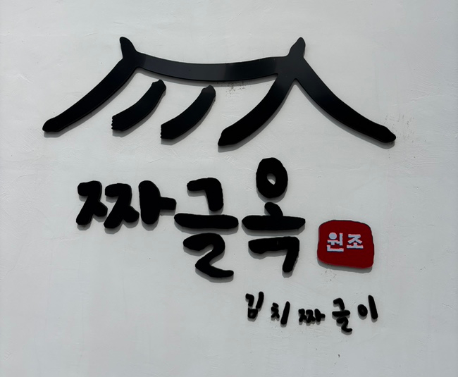 gagapp이 찍은 짜글옥의 손글씨 간판입니다. 기와지붕 모양으로 그려낸 글자 아래 '충주사과김치짜글이'라는 이름이 또렷합니다.