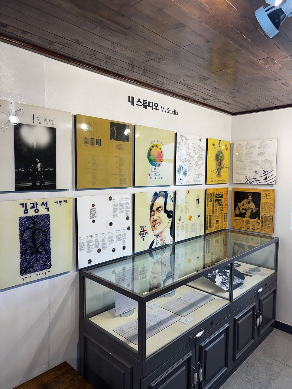 032_aizicima가 앉아 본 청음 자리와 '내 스튜디오' 벽입니다. 가죽 의자와 헤드폰만 놓인 조촐한 구성이지만 앨범을 순서대로 골라 들을 수 있다는 점을,