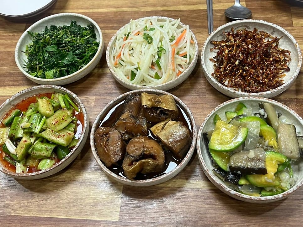 suklatte가 담은 벽면과 밑반찬 상입니다. 손글씨로 쓴 메뉴판과 낡은 벽걸이 달력에서 오래 그 자리를 지켜 온 가게임이 느껴지고,