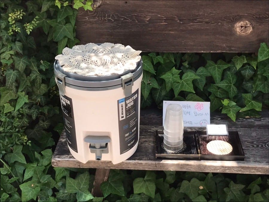 wakeup_log가 담은 정면과 야외 셀프바입니다. 흰 차양과 담쟁이 넝쿨, 화분들이 늘어선 입구가 골목 한복판에서도 한눈에 들어오고,
