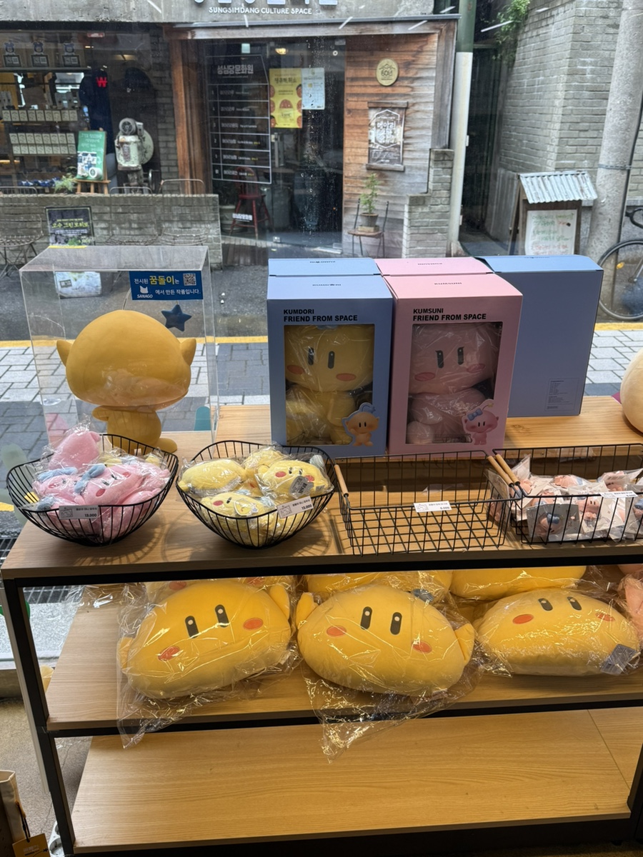 rkdchdus00이 남긴 에스닷 사진입니다. 성심당문화원이 건너편으로 보이는 매장 외관과, 쿰도리·쿰순이 인형이 진열된 내부 매대를 함께 담았습니다.
