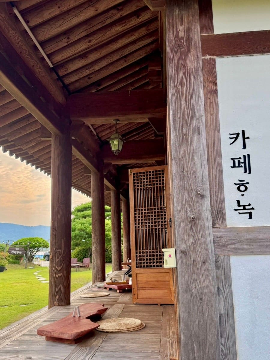 모찌 와플과 아몬드가 올라간 음료, '카페하녹' 이름표가 놓인 트레이입니다. 다른 사진은 한옥 처마 아래로 잔디밭이 트인 본채 마루, 벽에는 같은 이름이 한글로 걸려 있습니다.