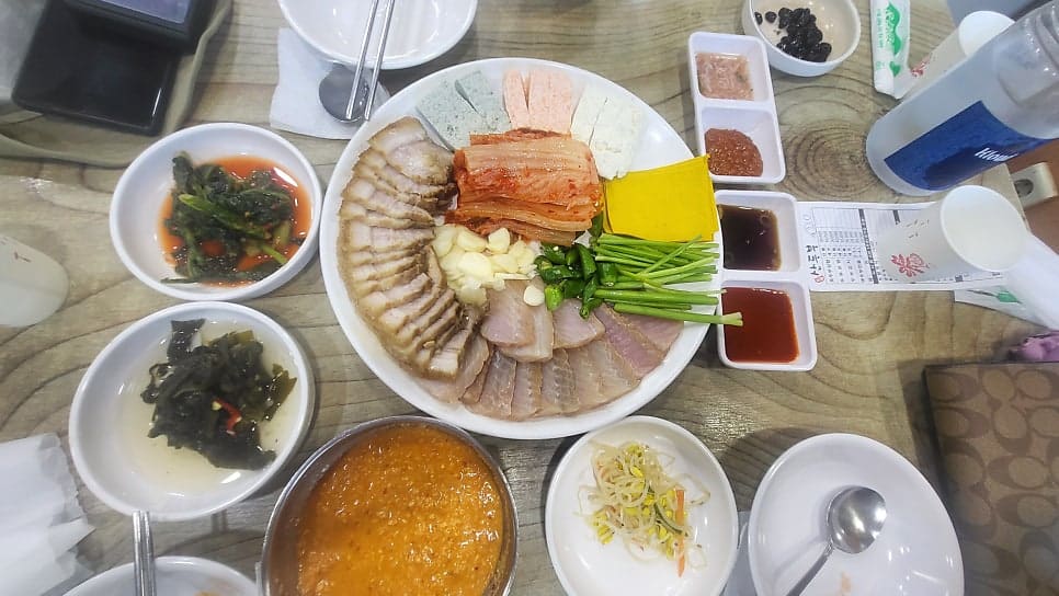 worthlog는 7년째 이 집을 찾는 단골입니다. 가게 앞에 세워진 메뉴판을 담았는데, 포두부삼합 35,000원부터 보쌈정식 14,000원까지 가격이 큼직하게 적혀 있습니다.
