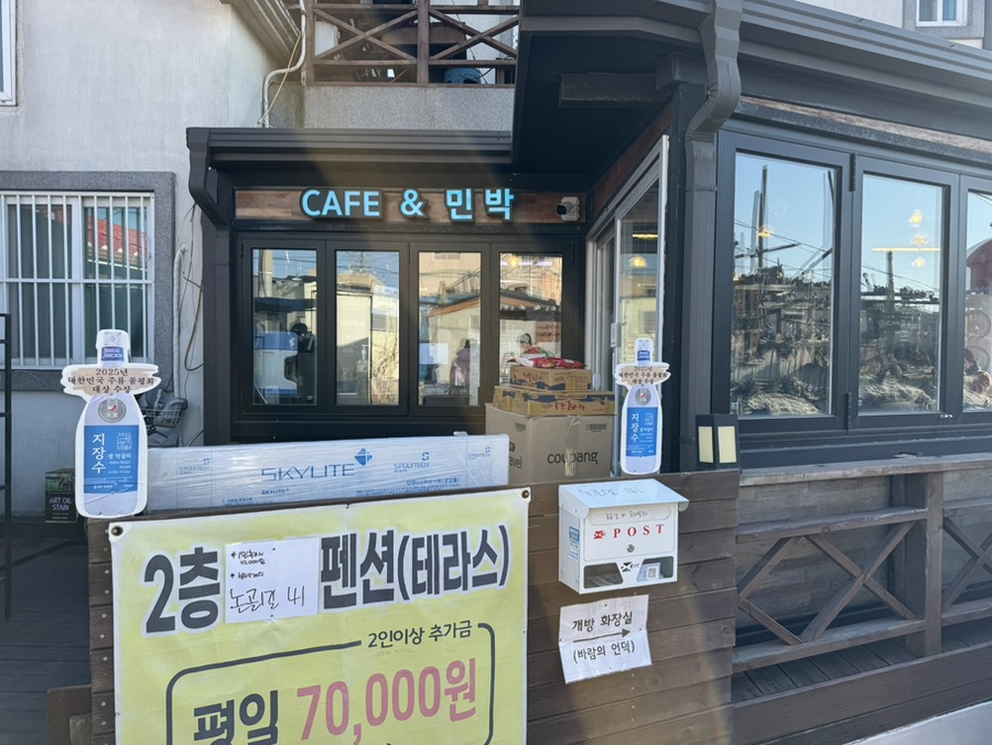 binijoa7이 담은 등대쉼터 외관입니다. '부추전/김치전/명태회무침' 메뉴를 적은 노란 간판과 '2층 테라스 펜션' 안내,