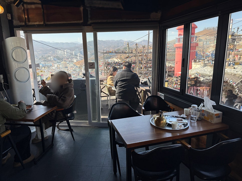 soulfultrip과 fleurdemimosa가 담은 실내입니다. 통창 너머로 묵호항과 분홍 등대 모형이 내려다보이는 1층 좌석과,