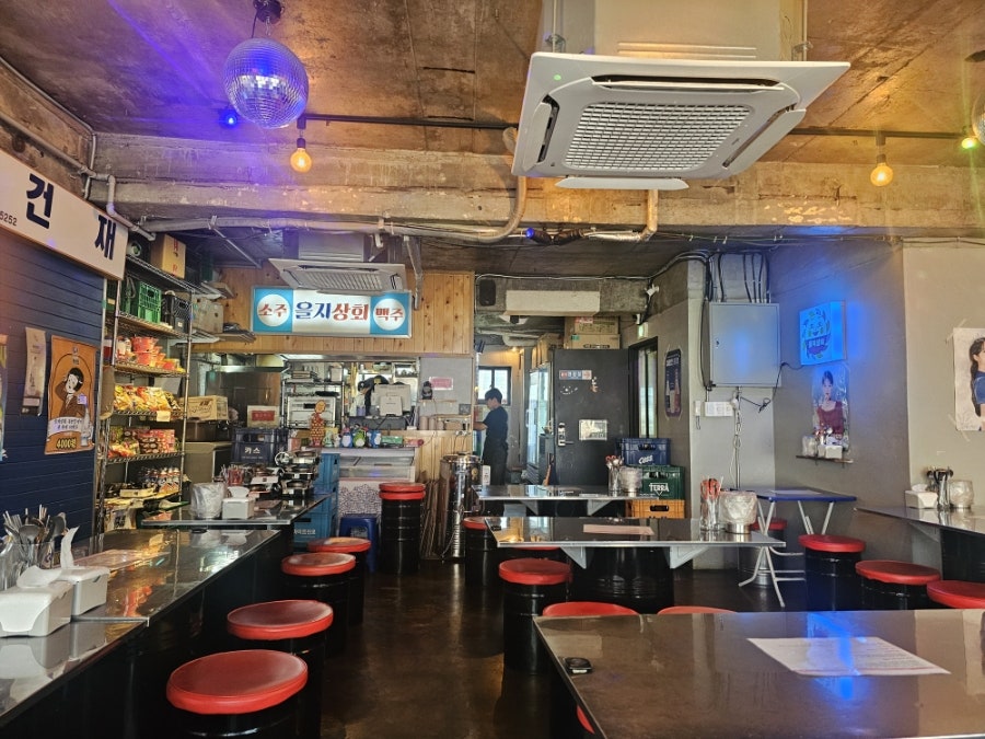 3daenam은 '소주 을지상회 맥주'라고 적힌 간판과 드럼통 의자가 늘어선 바 자리, 그리고 톱니 모양 해를 닮은 로고가 그려진 메뉴판을 찍었습니다.