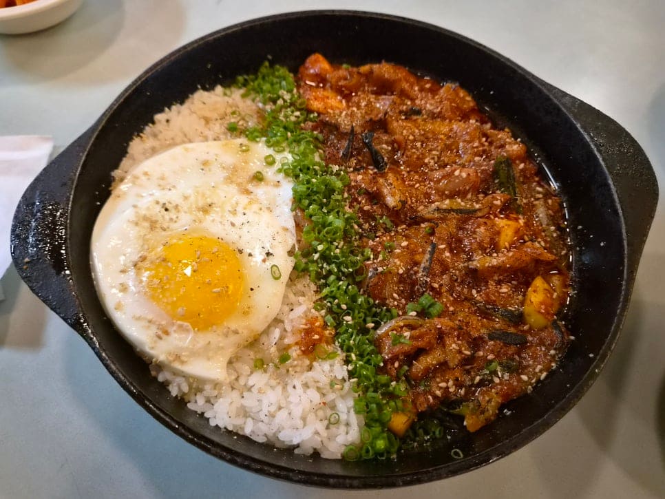 철판에 담긴 계육덮밥. 반숙 계란이 올려져 있고 쪽파가 곁들여진 덮밥이 보인다.