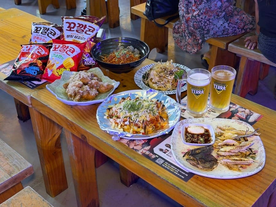 마늘 향 가득한 치킨과 생맥주의 조합. 한 블로거는 꼬깔콘 이벤트 소식에 반가워했고, 다른 블로거는 루프탑에서의 밤 풍경에 매료되었다. 같은 자리, 다른 시점.